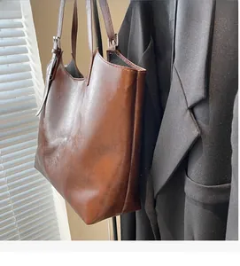 Detail of vintage brown oil wax leather tote bag with adjustable buckle strap on blazer