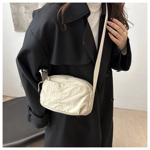 Detail view of the soft beige nylon crossbody bag texture with adjustable strap
