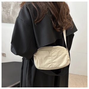 Detail of a beige nylon crossbody bag with adjustable strap shown on model side view