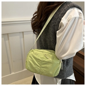 Close-up of light green crossbody bag featuring a front zipper with white rope puller