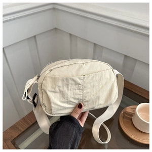 Detail of beige wrinkled nylon crossbody bag with wide shoulder strap and waterproof fabric
