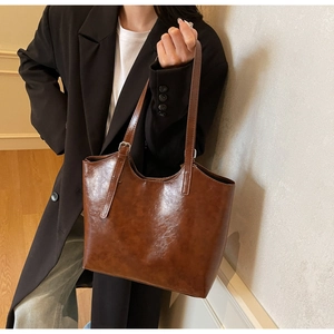 Detail showing vintage oil wax leather texture and long shoulder strap of the brown tote bag
