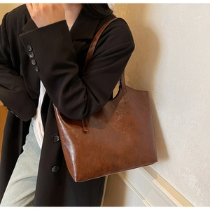 Detail of vintage brown tote bag with high-quality oil wax leather texture on black coat