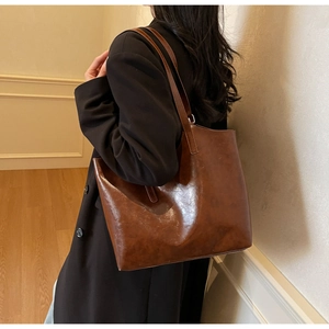 Detail of vintage brown tote bag showing glossy oil wax leather texture and shoulder strap