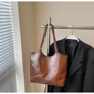 Detail of dark brown oil-wax leather tote bag with silver adjustable buckles and straps