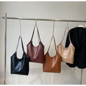 Detailed view of large tote bags in four colors hanging on a minimal steel display