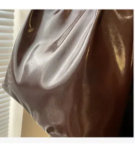 Detail of glossy brown oil leather texture and soft folded surface on the tote bag