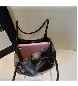 Interior detail of large chocolate tote bag with magnetic clasp holding a tablet and umbrella