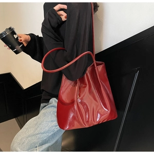 Red glossy tote bag worn by a model in a minimalist urban setting for a modern casual look