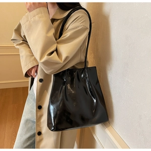 Glossy black patent leather tote bag shown on model for a minimalist commuting style