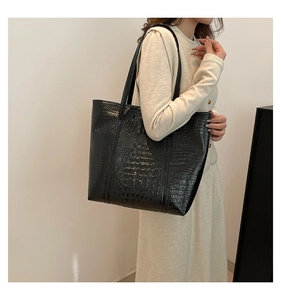 Close-up of a large black crocodile pattern tote bag shown on model for size and texture
