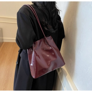 Detail of burgundy glossy tote bag shown on model for a premium minimalist commuter look