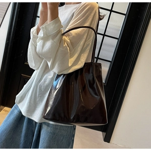 Detail of dark coffee patent leather tote bag with glossy finish on shoulder