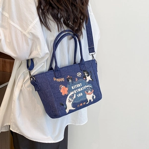 Borsa a mano in denim con motivi a gatto e tracolla regolabile indossata da una modella