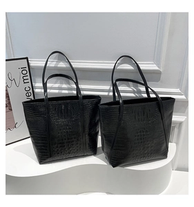 Detail of glossy black crocodile pattern texture on a stylish leather tote bag