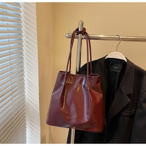 Close-up of deep wine red glossy tote bag with soft leather texture and stylish shoulder strap