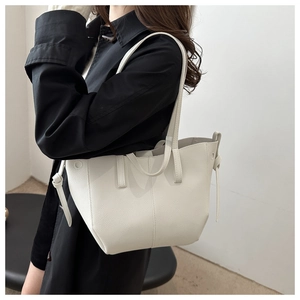 Detail of white lychee-patterned PU leather tote bag with stylish side knot decoration