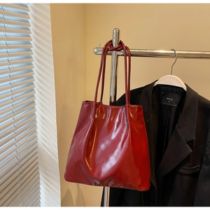 Detail of dark red glossy leather tote bag showing fine texture and slender straps