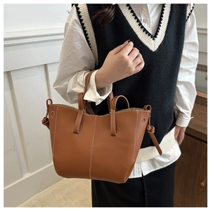 Close-up of brown litchi grain tote bag with white stitching and decorative knots