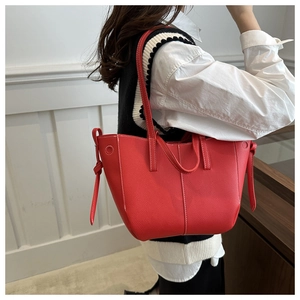 Détail du sac cabas en cuir grainé rouge avec surpiqûres blanches et nœuds latéraux