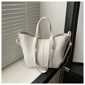 Detailed close-up of white lychee pattern PU leather tote bag with knotted side strap decor
