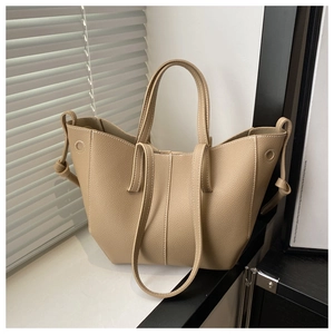 Detail of beige pebbled leather tote bag with contrast stitching and layered design