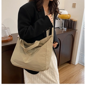 Beige canvas tote bag shown worn as a crossbody bag to display its large capacity size