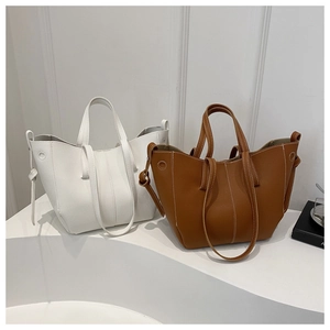 Detail of white and caramel PU leather tote bags with contrast stitching and dual straps