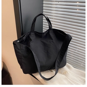 Detail of minimalist black canvas tote bag with wide shoulder strap and textured fabric