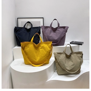 Macro shot of minimalist nylon tote bags in four colors on a white display stand