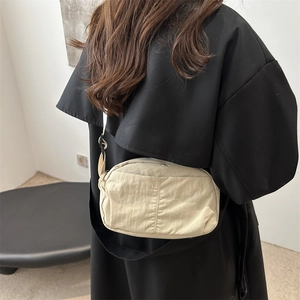 Minimalist beige nylon crossbody bag with adjustable shoulder strap for daily wear