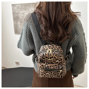 Close-up of leopard print mini backpack with gold hardware worn on model's back