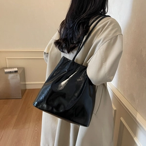 Minimalist black glossy tote bag with crinkled texture and long shoulder straps for women