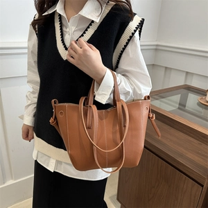 Brown PU leather tote bag with white stitching and side knot details shown in a lifestyle view
