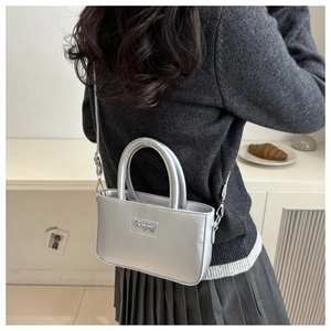 Close-up of silver metallic handbag featuring top handles and adjustable shoulder strap