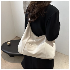 Close-up of cream large tote bag with stitching detail on a model in a black blazer