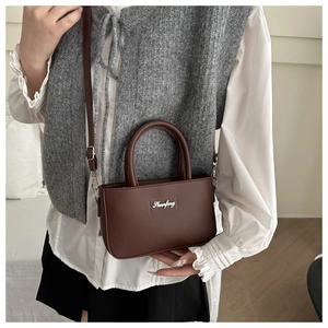 Detailed view of coffee brown leather bucket bag worn by a model in casual attire