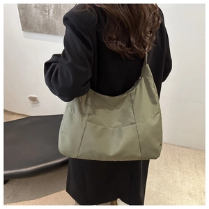 Detail of olive green nylon hobo bag showing zipper closure and minimalist panel design