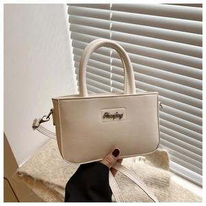 Detail of beige leather crossbody bucket bag with metallic logo and thin shoulder strap