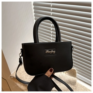 Detail of minimalist black square handbag with golden Shanfeng logo and elegant handle