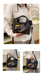 Detail of black faux leather tote bag with gold hardware and yellow mini bag charm