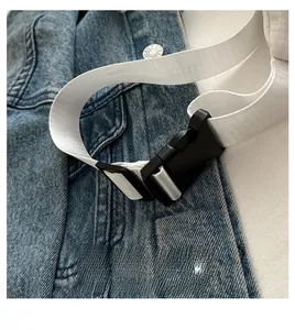 Detail of durable black plastic buckle and white nylon strap on denim fabric