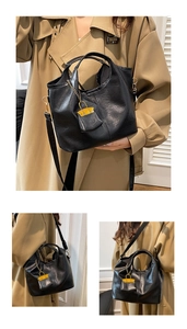Detail of black soft leather bucket bag showing the unique handle and mini pouch charm