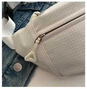 Close-up of smooth zipper closure with triangle puller on white checkered crossbody bag
