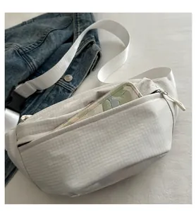 Detail of waffle pattern chest bag in cream with adjustable strap and quick-release buckle