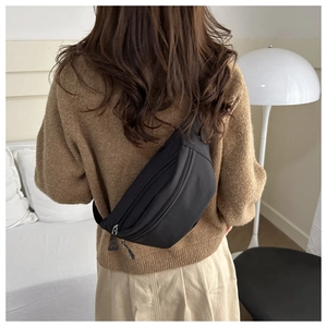 Detail of black nylon crossbody bag showing durable texture and layered zippers