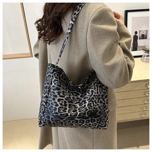 Detail of large leopard print canvas tote bag styled with a camel wool coat in a home setting