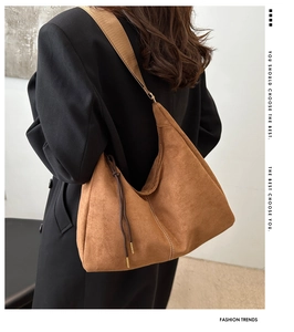 Detail of a brown suede Hobo bag with white stitching and side drawstring details