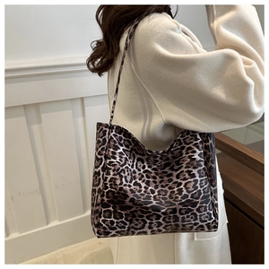Detailed side view of a large leopard print tote bag worn on the shoulder by a model
