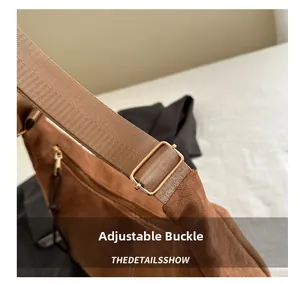Detail of adjustable golden buckle and wide textile strap on brown suede tote bag